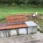 Eine Bank an einem Wohngebiet, das langsam in den Himmel wächst. Eine Bank zum Feiern. Eine Bank zum Sterben.